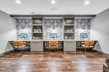An office space with two desks and chairs and a counter with two computers